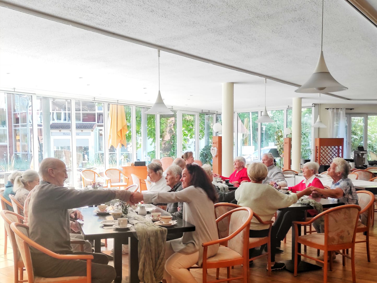 Eine Gruppe von Bewohnern sitzt an zwei Tischen verteilt und trinken gemeinsam Kaffee